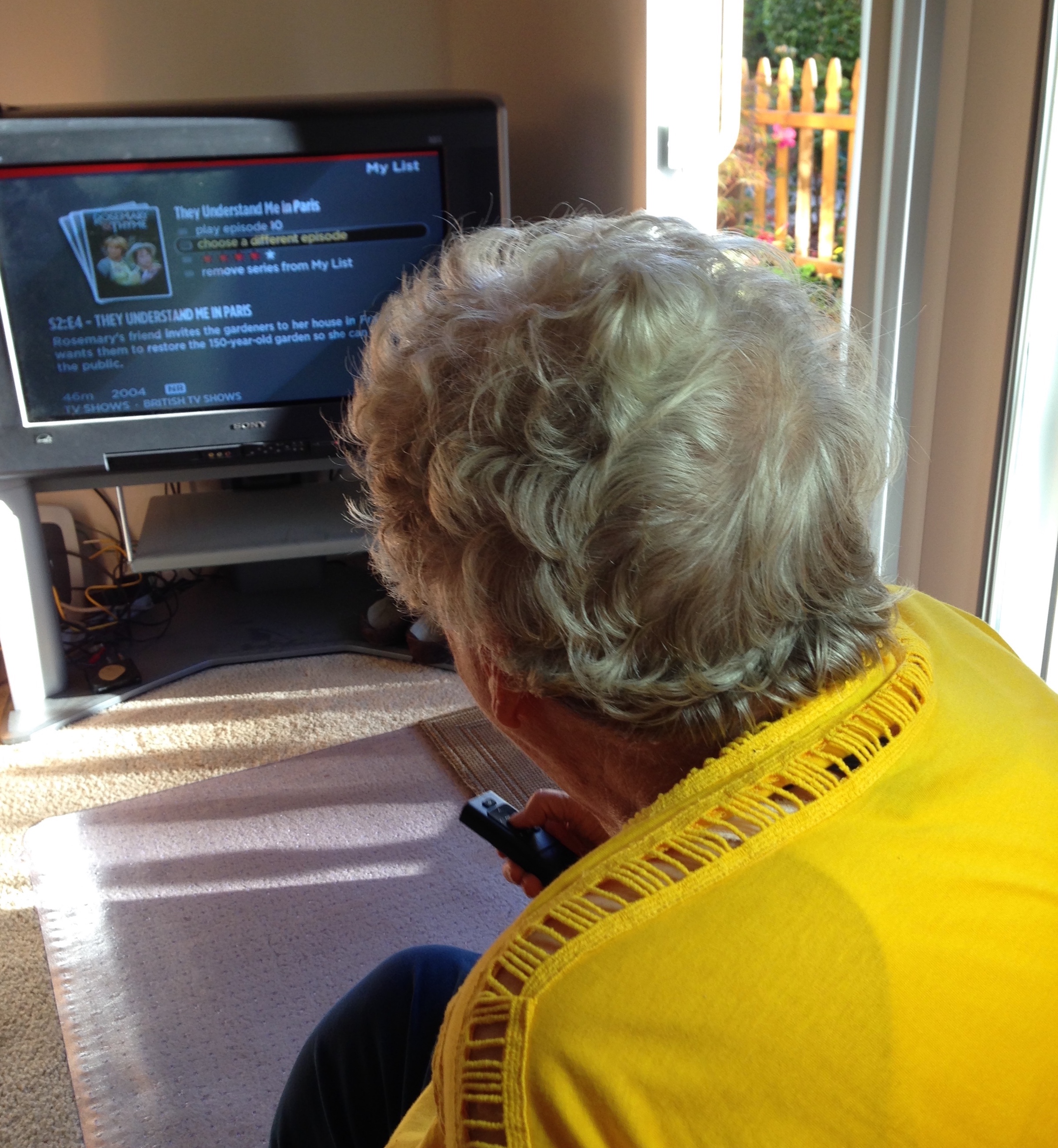 older woman operating a television with a remote that she is holding